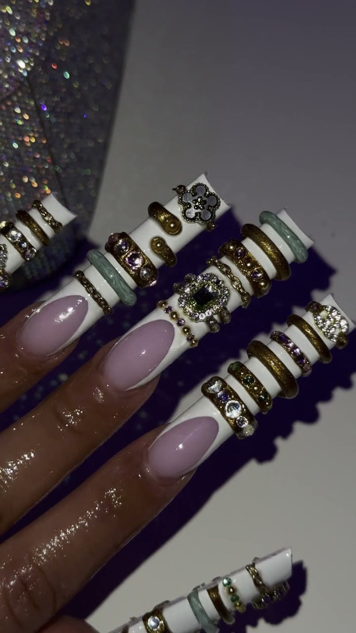 Real hand wearing extra-long square VENOM PRESSD nails with layered gold, mint, crystal and charm details.